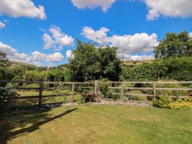A garden with a fence and trees at Buzzards Breg in Builth Wells