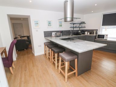 A kitchen with a large island and four stools at Rose Bank Cottage in St Just