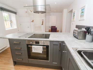 A kitchen with a built in oven stovetop sink toaster and utensils at Rose Bank Cottage in St Just