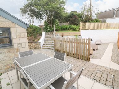 An outdoor patio area with a table and chairs stone steps and a small fenced garden at Rose Bank Cottage in St Just