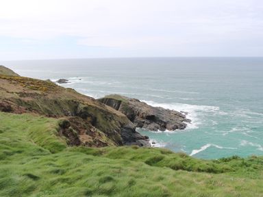 A coastal cliff with grass and rocky outcrops overlooking the sea at Rose Bank Cottage in St Just