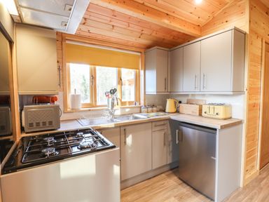 A kitchen with gas stove microwave sink and kettle at Buttercup Lodge in Theberton near Leiston