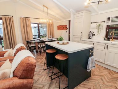 A kitchen and dining area with a kitchen island and bar stools at The Treeline in Swarland near Felton