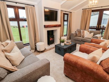 A living room with sofas armchairs a fireplace and a television at The Treeline in Swarland near Felton
