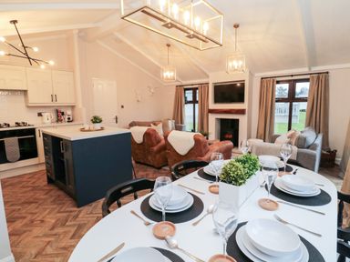 An open plan kitchen and living area with a dining table set with plates and glasses at The Treeline in Swarland near Felton