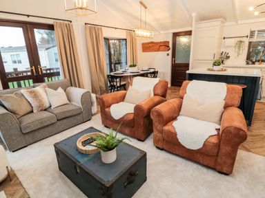 A living room with two brown armchairs a grey sofa and a black coffee table at The Treeline Swarland near Felton