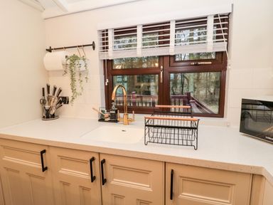 A kitchen countertop with sink faucet paper towel holder knife set and microwave by a window at The Treeline in Swarland near Felton