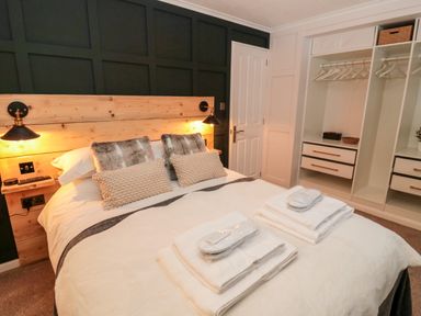 A bedroom with a bed with pillows towels and slippers and open closet space at The Treeline in Swarland near Felton