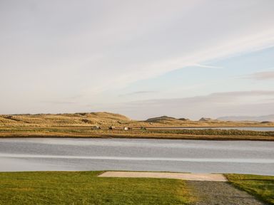 A body of water with grass in the foreground and hills in the background at The Beachhouse in Meenlaragh near Gortahork County Donegal
