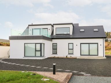 A modern two-story house with large windows and a glass balcony at The Beachhouse in Meenlaragh near Gortahork County Donegal