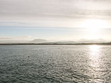 A body of water with a distant shoreline and mountains under a cloudy sky at The Beachhouse in Meenlaragh near Gortahork County Donegal
