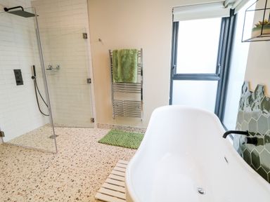 A bathroom with a freestanding bathtub shower area towel rack and window at The Beachhouse in Meenlaragh near Gortahork County Donegal