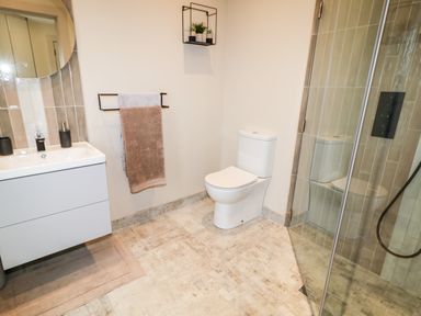 A bathroom with a toilet sink with mirror towel rack and glass shower enclosure at The Beachhouse in Meenlaragh near Gortahork County Donegal