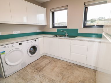 A utility room with washing machine dryer sink and countertops at The Beachhouse in Meenlaragh near Gortahork County Donegal