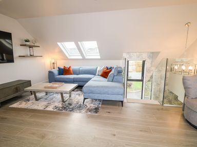 A living room with a blue sectional sofa and orange pillows under skylight windows at The Beachhouse in Meenlaragh near Gortahork County Donegal