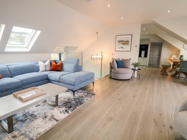 A living room with a blue sectional sofa a coffee table a round chair and a dining area at The Beachhouse in Meenlaragh near Gortahork County Donegal