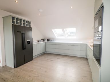 A kitchen with built-in cabinets under skylights and a black refrigerator at The Beachhouse in Meenlaragh near Gortahork County Donegal