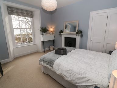 A bedroom with a bed towels on it a window and a fireplace at Belmont in Newlyn