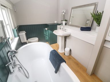 A bathroom with a bathtub a sink a toilet a mirror and plants at Belmont in Newlyn