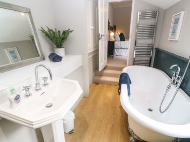 A bathroom with a white sink and a freestanding bathtub with a faucet and towel at Belmont in Newlyn