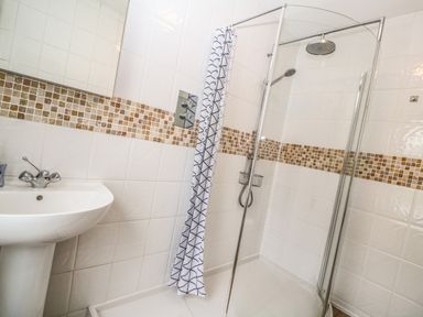A bathroom with a sink and a shower area with a glass door and a shower curtain at Belmont in Newlyn