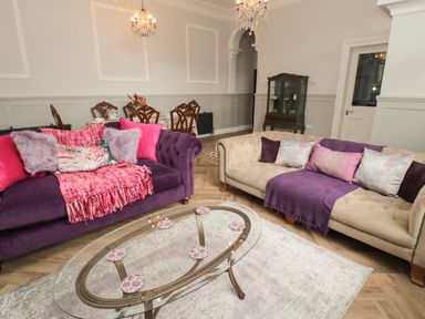 A living room with purple and beige sofas a glass coffee table and a dining table with chairs at The Vault House in Bellingham