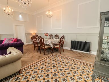 A dining room with a wooden table and chairs a beige and purple sofa and a display cabinet at The Vault House in Bellingham