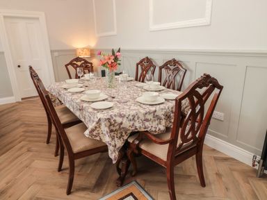 A dining room with a wooden table set for six with floral tablecloth and flower vase at The Vault House in Bellingham