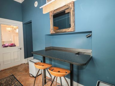 A kitchen area with a black countertop bar and two wooden stools with a gold framed mirror on a blue wall at The Vault House in Bellingham