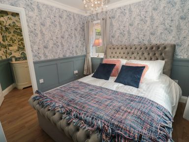 A bedroom with a tufted bed headboard pillows a patterned blanket window and curtains at The Vault House in Bellingham
