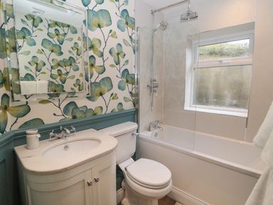 A bathroom with a sink, toilet, bathtub with shower, and window at The Vault House in Bellingham