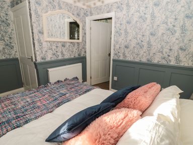 A bedroom with patterned wallpaper a bed with pillows a mirror and an open door at The Vault House in Bellingham