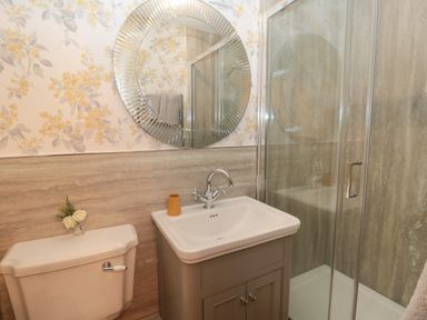 A bathroom with a toilet shower sink with cabinet and round mirror at The Vault House in Bellingham