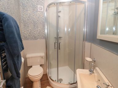A bathroom with a corner shower enclosure, a toilet, a sink, and blue towels hanging on a rack at The Vault House in Bellingham