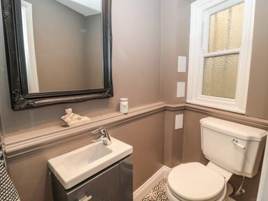 A bathroom with a sink and cabinet a toilet a window and a large mirror at The Vault House in Bellingham