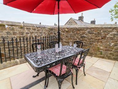 An outdoor patio with a black metal table and chairs under a red umbrella at The Vault House in Bellingham