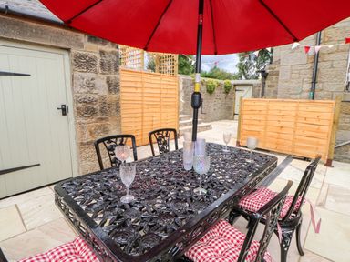 An outdoor patio area with a black metal table and chairs under a red umbrella with red and white cushions on the chairs at The Vault House in Bellingham