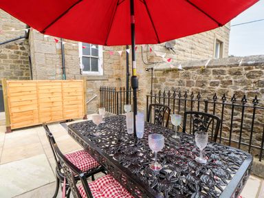 An outdoor patio with a black metal table and chairs with red cushions and a red umbrella at The Vault House in Bellingham