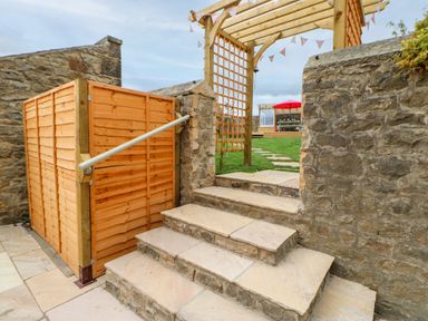 Stone steps leading up to a wooden pergola and grassy yard with a red umbrella in the background at The Vault House in Bellingham