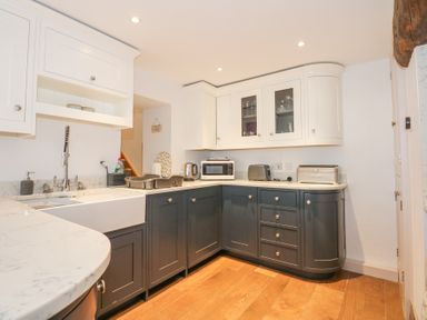 A kitchen with white and dark grey cabinets wooden floor and countertop appliances at Min Y Mor - Morfa Nefyn