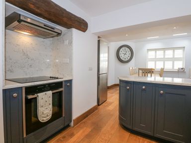A kitchen with an oven stovetop and a wooden beam above a countertop at Min Y Mor - Morfa Nefyn