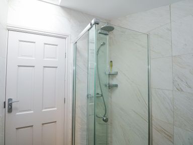 A bathroom with a shower enclosure and a closed white door at Min Y Mor - Morfa Nefyn