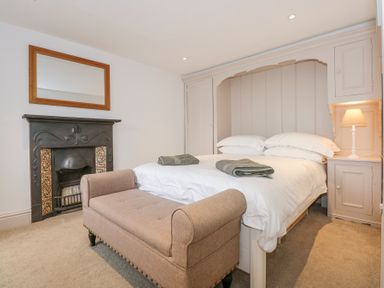 A bedroom with a bed and towels by a fireplace mirror and bedside lamp at Min Y Mor - Morfa Nefyn