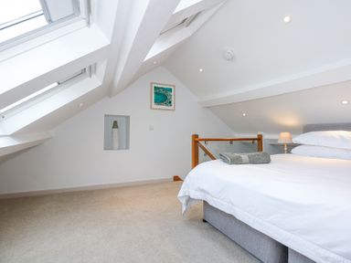 A bedroom with a bed lamp and skylight windows at Min Y Mor - Morfa Nefyn