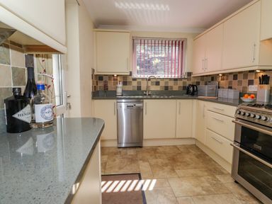 A kitchen with cream cabinets a stainless steel oven dishwasher and sink at Primrose Cottage in Ambleside