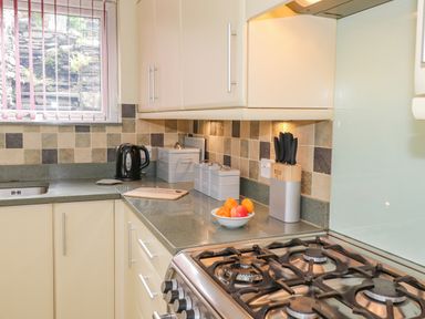 A kitchen with a gas stove cutting board kettle and knife block at Primrose Cottage Ambleside