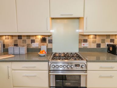 A kitchen with a stove an oven a knife block containers a bowl with fruit and a toaster at Primrose Cottage in Ambleside