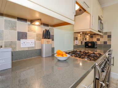 A kitchen countertop with a gas stove a bowl of fruit a knife block and a toaster at Primrose Cottage Ambleside
