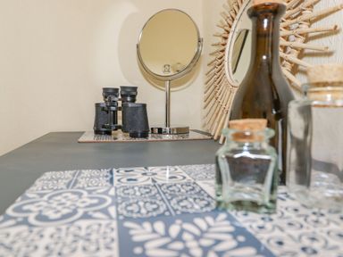 A table with binoculars a round mirror and glass jars with cork lids at Primrose Cottage in Ambleside