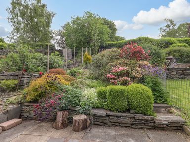 A garden with shrubs flowers and stone steps at Primrose Cottage in Ambleside